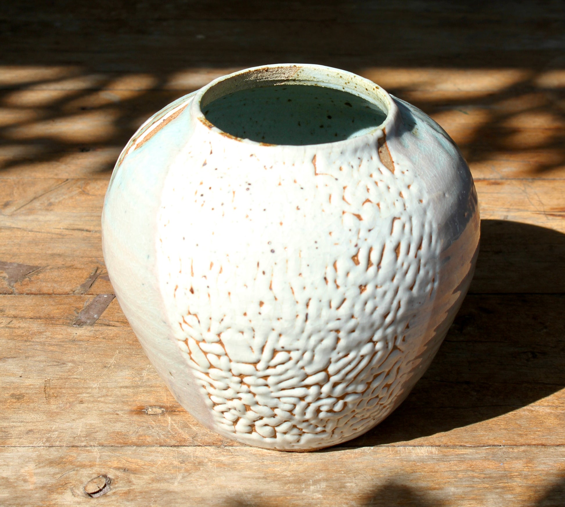 wheel thrown vase with a surface glazed in a traditional Japanese crawling Shino and wood ash glaze that allows the glimpses of the unglazed clay body to peak through.